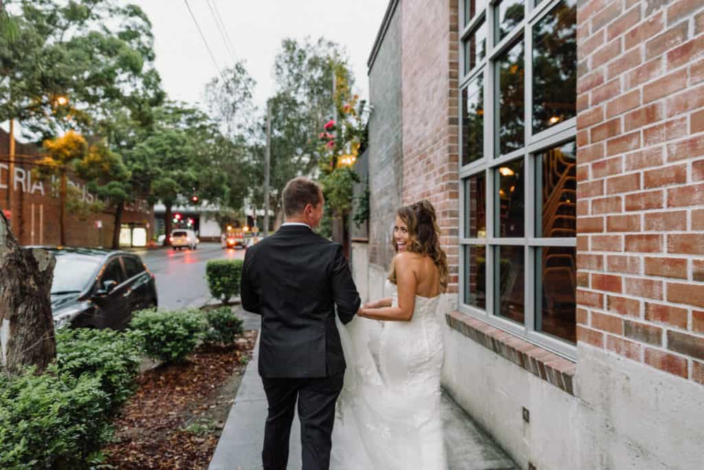 bride and groom hold hands walking down urban street captured by james white photography