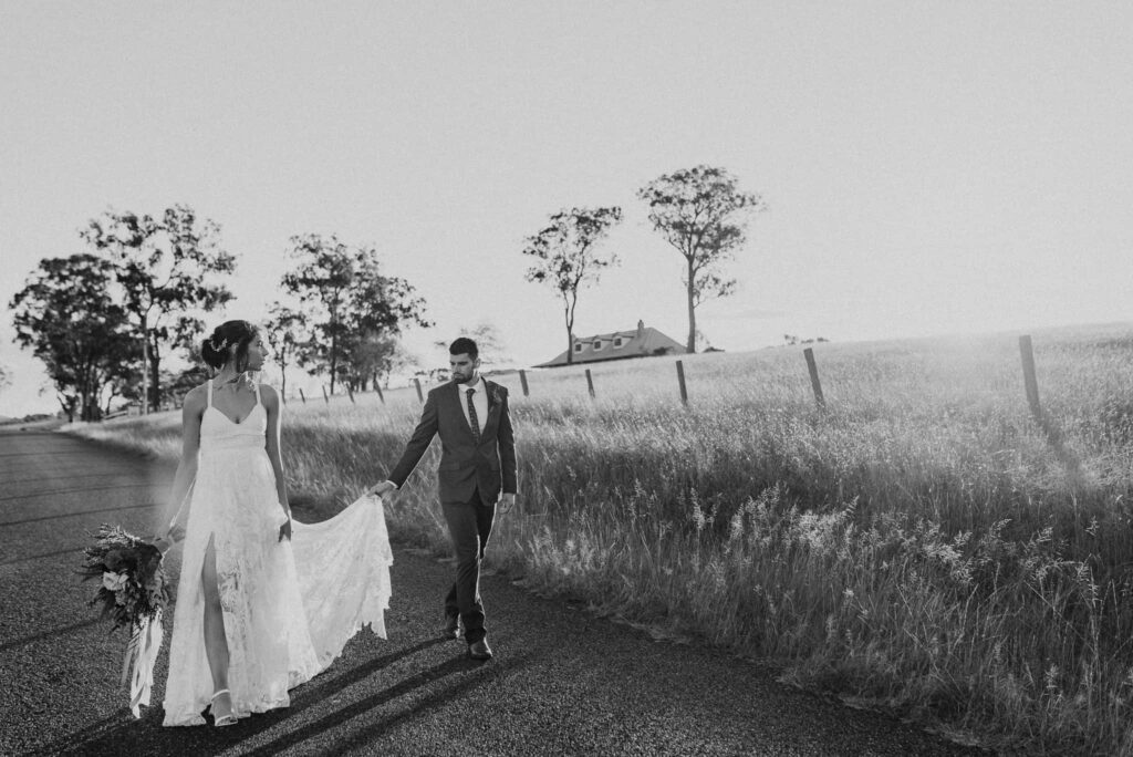 bride and gro walk down country road outside estate tuscany as sun sets over the fields captured by james white hunter valley wedding photographer