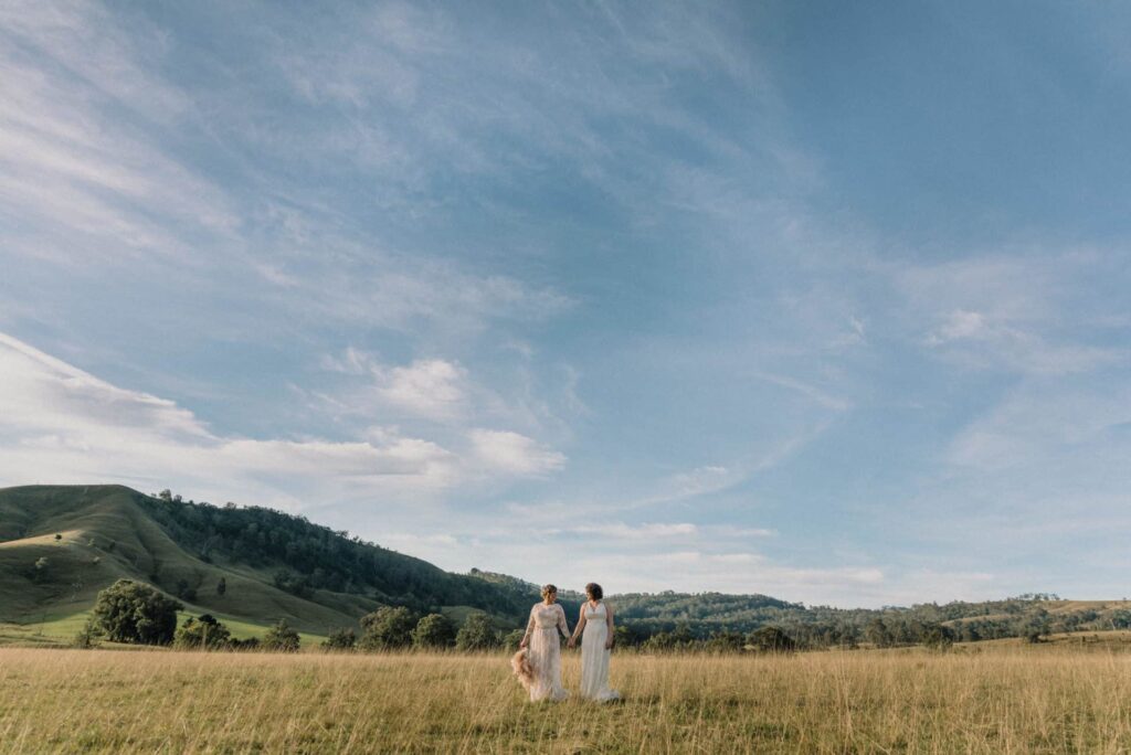 two brides embracing in a golden field under the Australian sun at Lynwood hunter valley wedding venue favourite