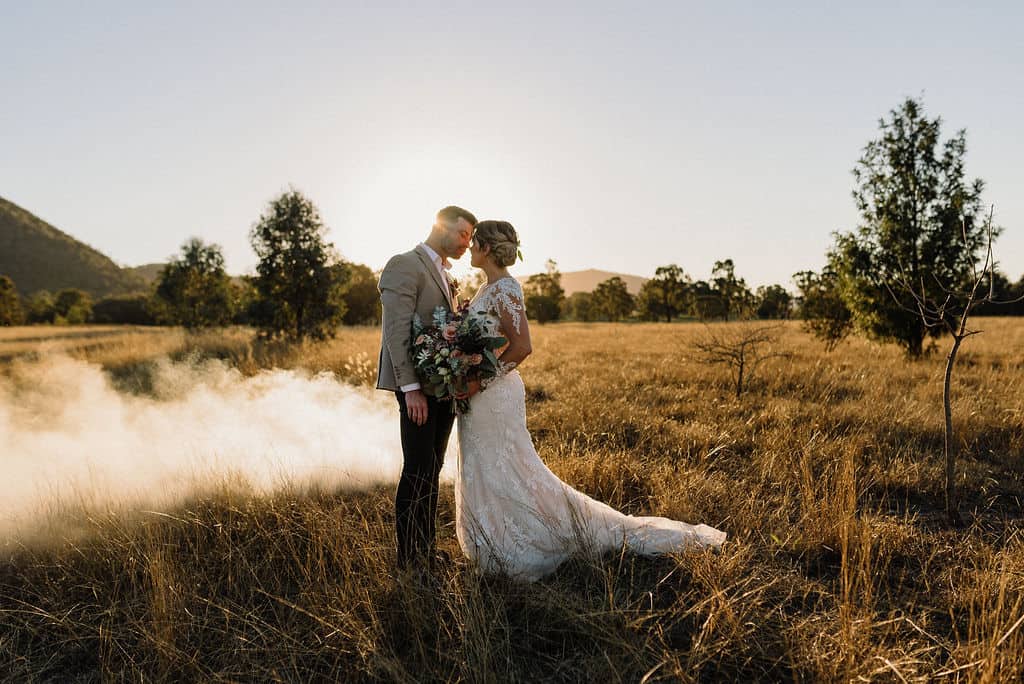 bride and groom enjoying first kiss as the sun sets across a field behind them in the gorgeous hunter valley