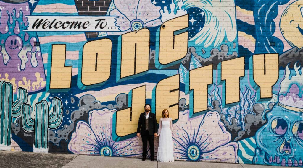 bride and groom pose against graffiti wall in long jetty the savoy long jetty wedding