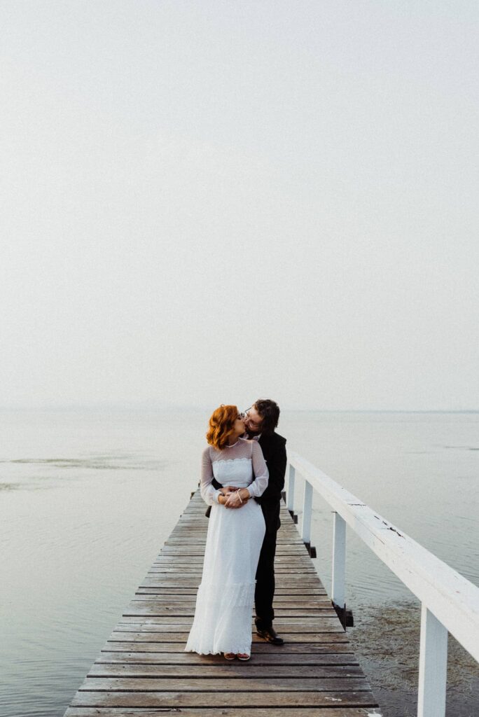 bride and groom posing for epic portraits on the jetty on the lake at the savoy long jetty wedding