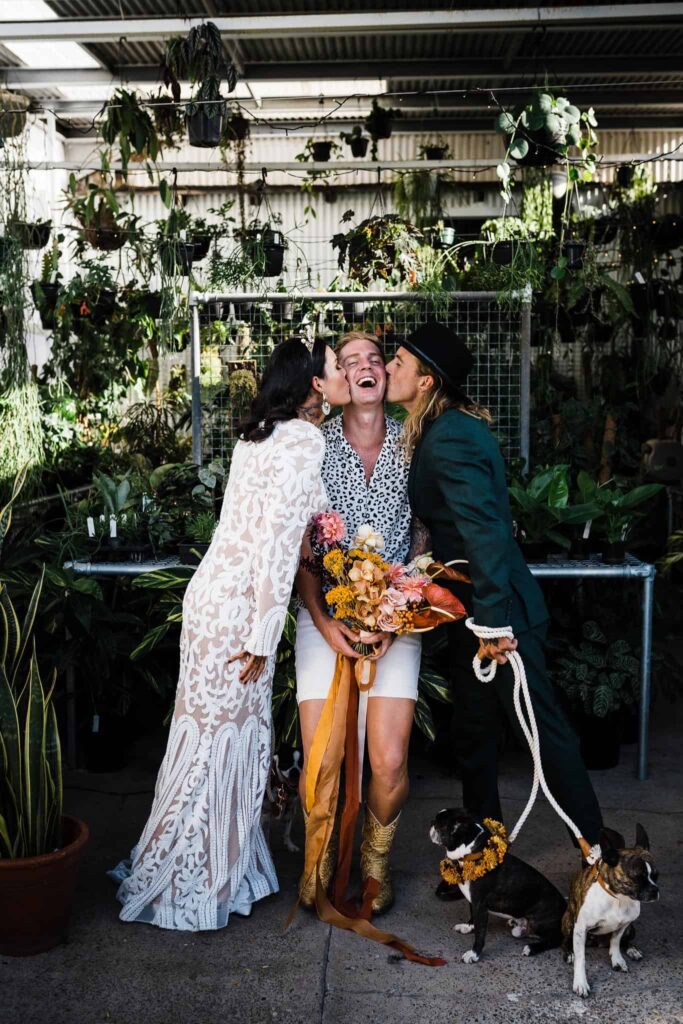 bride and groom kissing celebrant monty harron after wedding ceremony in greenhouse