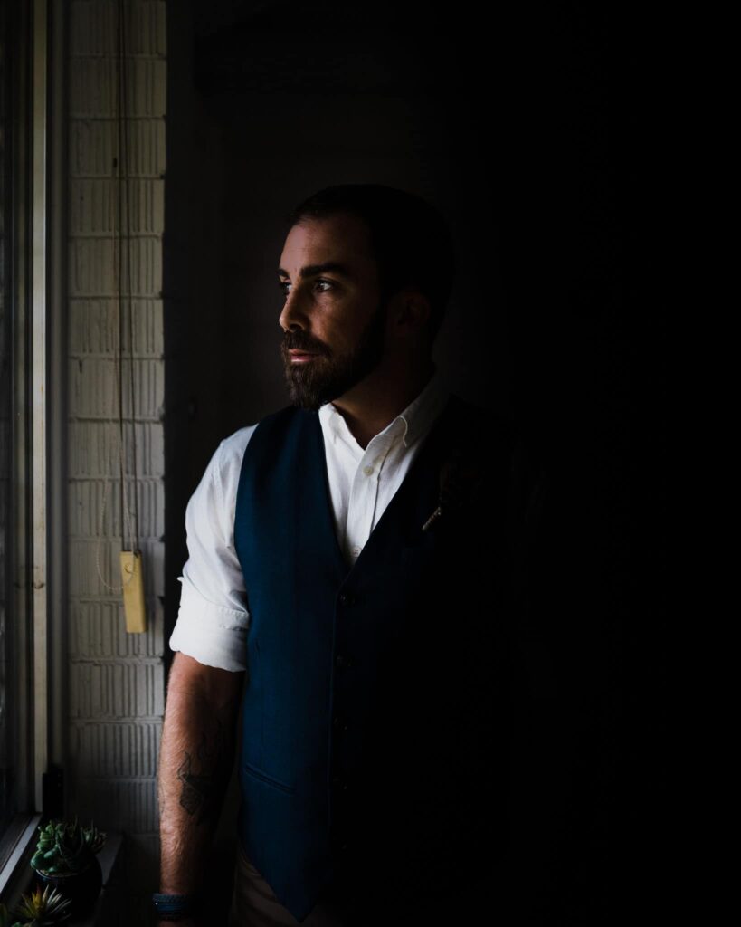 masculine elegant shot of groom posing in front of window before wedding ceremony captured by james white newcastle wedding photographer