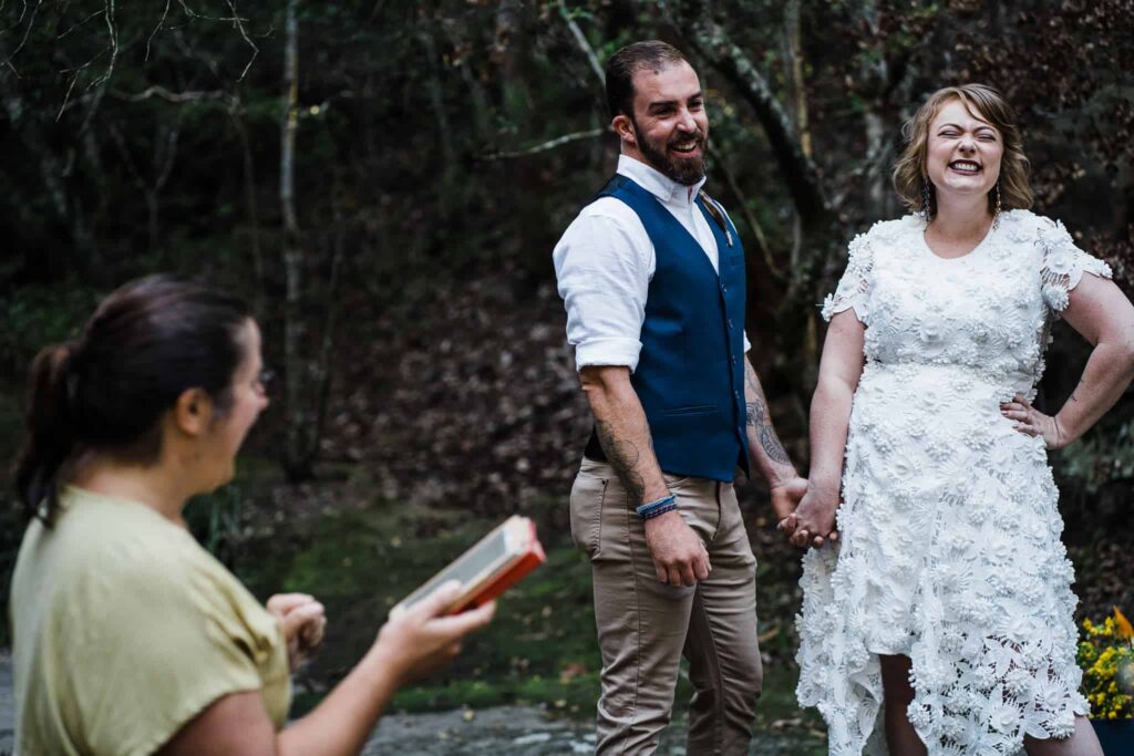 bride and groom laughing at celebrant during elopement ceremony Glenrock captured by james white newcastle wedding photographer