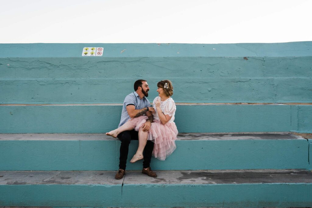 bride and groom sitting on blue steps at newcastle baths captured by james white newcastle wedding photographer